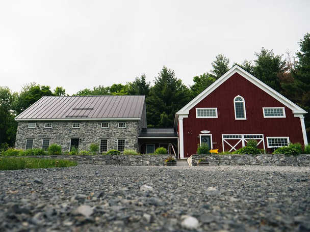 A low angle shot of a modern stone house connected to a barn house with trees in the background - 写真・画像