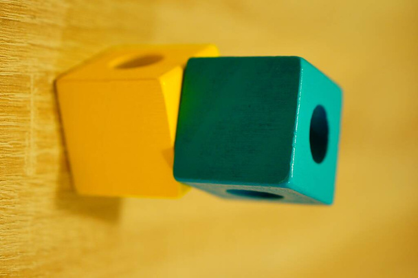 Een verticale close-up shot van speelgoed blokken op een houten oppervlak met een wazige achtergrond - Foto, afbeelding