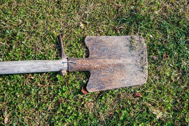 A high angle shot of an old shovel laid on a grass ground - Foto, immagini