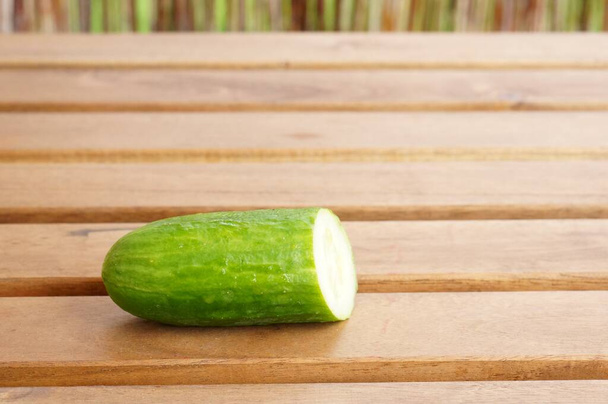 A closeup shot of a fresh piece of cucumber on a wooden surface - Photo, Image