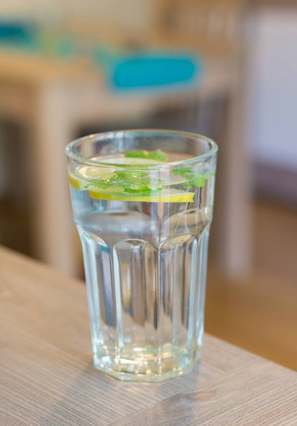 Un primo piano verticale di un bicchiere d'acqua con limone e menta con sfondo sfocato
 - Foto, immagini
