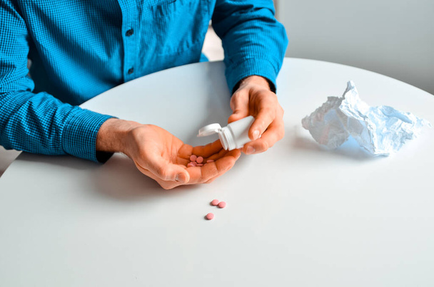Shot of a young man holding a jar with a pills at home. Actual problem, cold and chill, background for medical design - Photo, Image