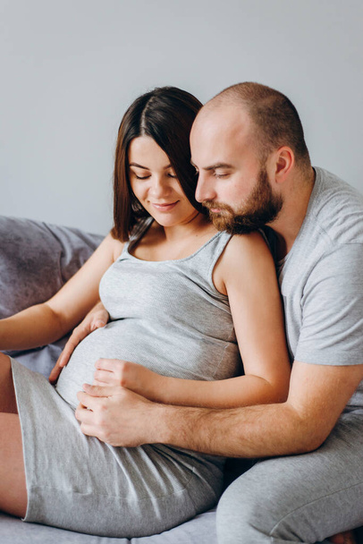 Schwangerschaft. Junges Paar wartet auf Baby. Wunderbare werdende Eltern kuscheln in ihrer Wohnung und warten auf die Geburt - Foto, Bild