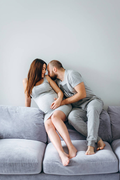 妊娠中。赤ん坊を待っている若いカップル。素晴らしい期待の両親抱っこで彼らのアパート出産を待っています - 写真・画像