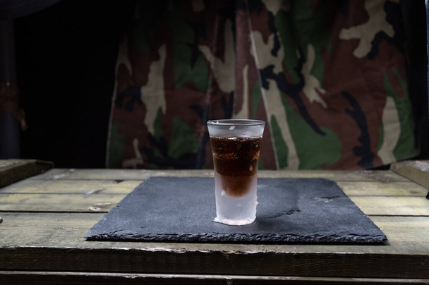Холодный стакан с темной выпивкой. Стакан ликера.
. - Фото, изображение