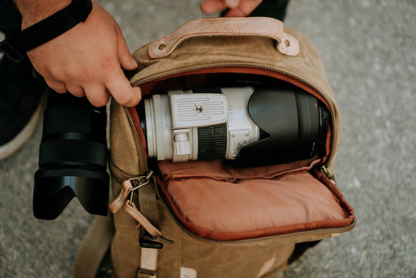 Fotograf wyciągający białą soczewkę aparatu fotograficznego z torby - Zdjęcie, obraz