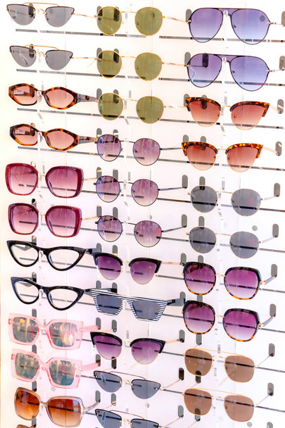 Stand with many sunglasses in a store of optics. Side close up view. - Fotó, kép
