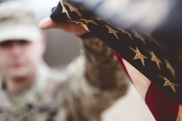 A shallow focus shot of an American soldier holding the American flag - Foto, immagini