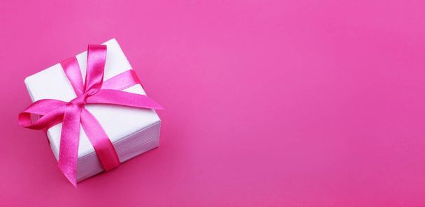 gift box with pink ribbon on pink background. banner. top view. copy space. - Foto, Bild