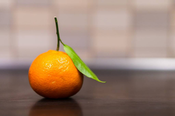 A selective focus shot of green leaf of orange fruit with a blurred background - Foto, Bild