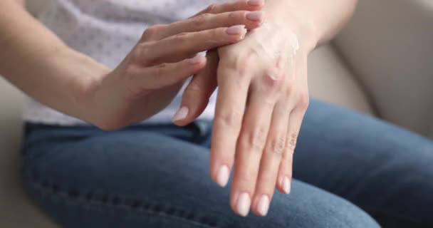 Young woman applying moisturizing cream on hands, close up view - Video