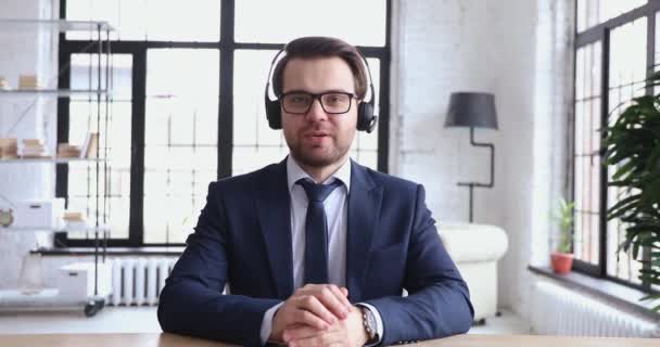 Confident support service representative wears headset talking to webcam - Séquence, vidéo