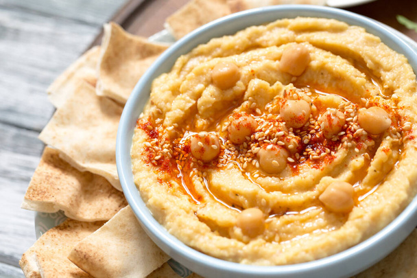 A bowl of creamy homemade hummus with olive oil and pita chips. traditional vegan healthy meal. - Photo, Image