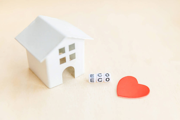 Miniaturowy model domu z napisem ECO litery słowo na drewnianym tle. Eco Village abstrakcyjne środowisko. Ekologia zero odpadów Odpowiedzialność społeczna recyklingu bio domu koncepcja - Zdjęcie, obraz