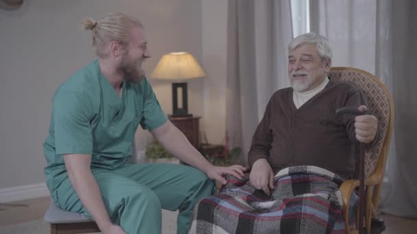 Portrait of joyful old man joking and laughing out loud with male nurse indoors. Mature Caucasian retiree having fun in nursing home. Joy, lifestyle, leisure, support. - Séquence, vidéo