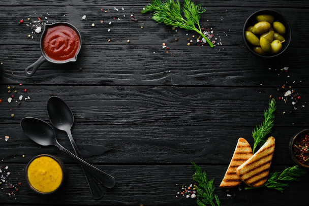 The background of cooking. A set of spices and fresh vegetables. Top view. Free space for your text. On a black stone background. - Foto, afbeelding