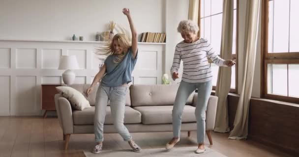 Overjoyed young lady dancing with excited middle aged elderly mother. - Video