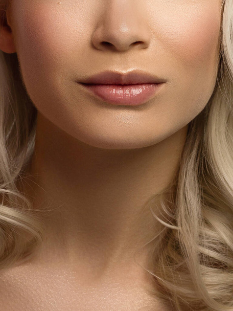 Close-up of woman's lips with fashion natural beige lipstick makeup. Macro sexy pale lipgloss make-up . Gentle pure skin and wavy blonde hair. Cosmetology, Spa, increase in lips. Face powder - Fotografie, Obrázek