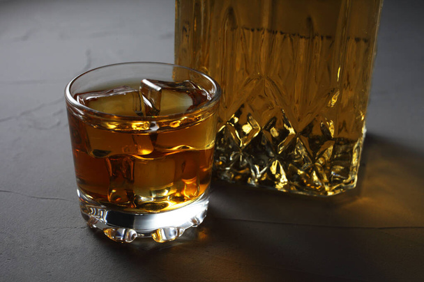 Szklany rum z lodem, karafka z rumem na betonowym tle zbliżenie - Zdjęcie, obraz