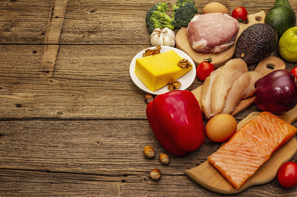 Set de productos dietéticos cetogénicos de moda. Paleo, pegan nutrición baja en carbohidratos. Carne, pescado, queso, frutas y verduras. Tableros de madera fondo
 - Foto, imagen