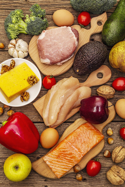 Trendy ketogene dieetproducten set. Paleo, pegan lage koolhydraten voeding. Vlees, vis, kaas, fruit en groenten. Houten planken achtergrond, bovenaanzicht - Foto, afbeelding