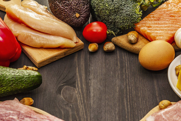 Set di prodotti dietetici chetogeni alla moda. Paleo, pegan basso contenuto di carboidrati nutrizione. Carne, pesce, formaggio, frutta e verdura. Tavole di legno nero sfondo
 - Foto, immagini
