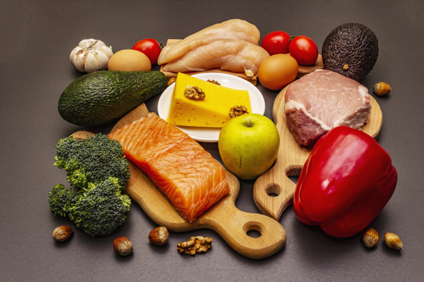 Set de productos dietéticos cetogénicos de moda. Paleo, pegan nutrición baja en carbohidratos. Carne, pescado, queso, frutas y verduras. Fondo de hormigón de piedra negra
 - Foto, Imagen