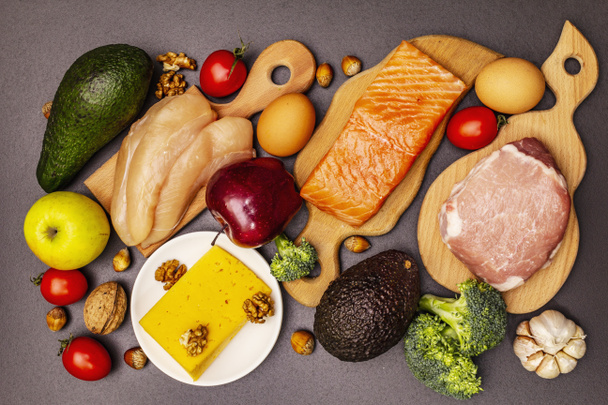 Set de productos dietéticos cetogénicos de moda. Paleo, pegan nutrición baja en carbohidratos. Carne, pescado, queso, frutas y verduras. Fondo de hormigón de piedra negra
 - Foto, imagen
