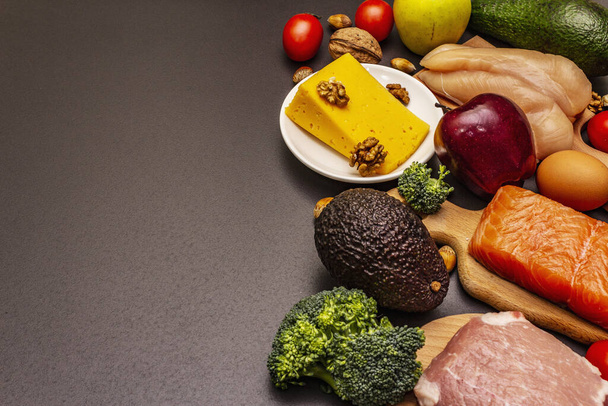 Set di prodotti dietetici chetogeni alla moda. Paleo, pegan basso contenuto di carboidrati nutrizione. Carne, pesce, formaggio, frutta e verdura. Pietra nera sfondo di cemento
 - Foto, immagini