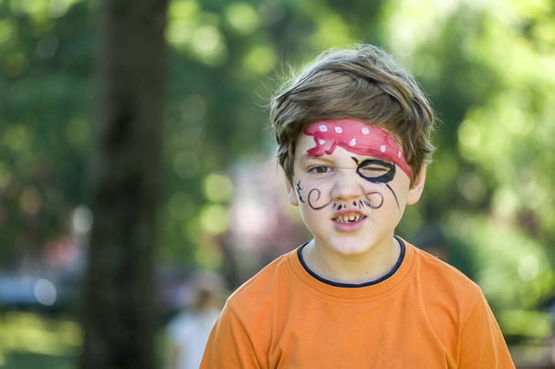 Child making funny faces. Kid with a pirate painting on his face. - Foto, immagini