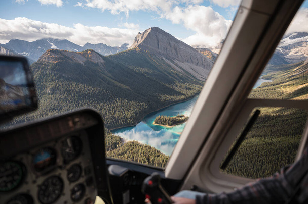 Inside of helicopter flying on rocky mountains with colorful lake in national park - Photo, Image