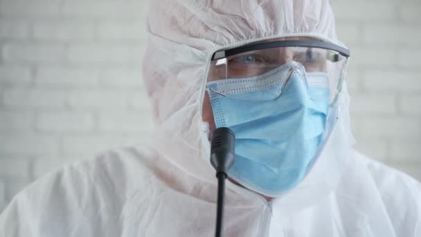 Slow Motion with a Doctor Wearing a Protection Suit and Talking in a Medical Press Conference About Coronavirus Epidemic - Materiał filmowy, wideo