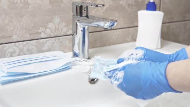 Крупный план женских рук, стирающих одноразовую медицинскую маску для лица с мылом. Дефицит средств личной гигиены во время эпидемии или пандемии. Концепция здравоохранения
 - Кадры, видео