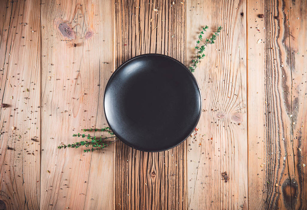 Empty black plate on wooden table. Food invitation. Ready to serve and cook fresh meal. Copy empty space. Top view - flat lay - Photo, Image
