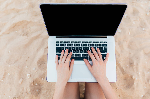 Primer plano de las manos escribiendo en un ordenador portátil, de vacaciones en la playa
 - Foto, imagen