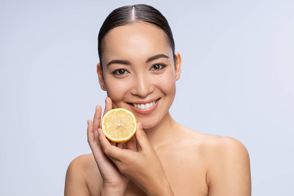 Beautiful female holding fresh lemon near face - Φωτογραφία, εικόνα