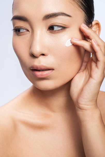 Asian young woman with cosmetic cream on her cheek - Fotoğraf, Görsel