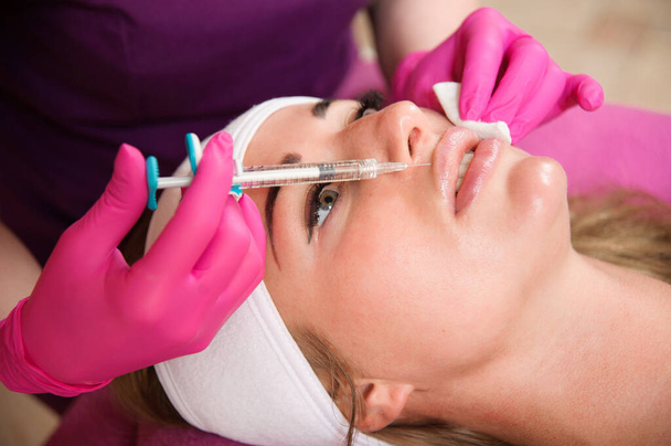 Beautician doctor hands doing beauty procedure to female lips with syringe. Cosmetic medicine and surgery, beauty injections concept - Photo, Image