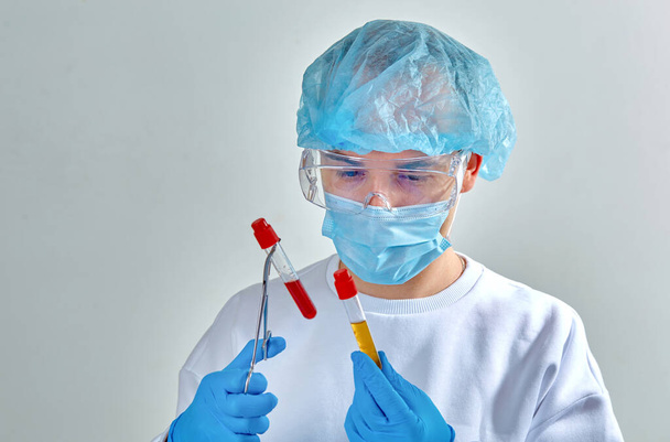 Lekarz w masce wykonujący badania krwi na obecność koronawirusa COVID19, HIV, ebola lub innego niebezpiecznego zakażenia, choroby. Portret lekarza, medyczne tło, szablon, tapeta. Choroba koronawirusowa  - Zdjęcie, obraz