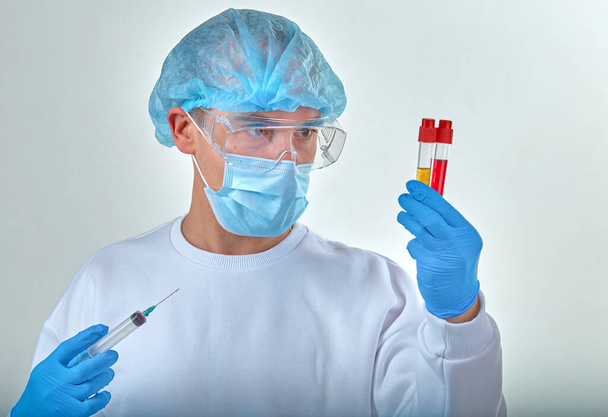 Médico mascarado realizando exame de sangue para coronavírus COVID19, HIV, ebola ou outra infecção perigosa. Fundo médico, instrumentos, modelo, papel de parede. Conceito de doença por coronavírus
 - Foto, Imagem