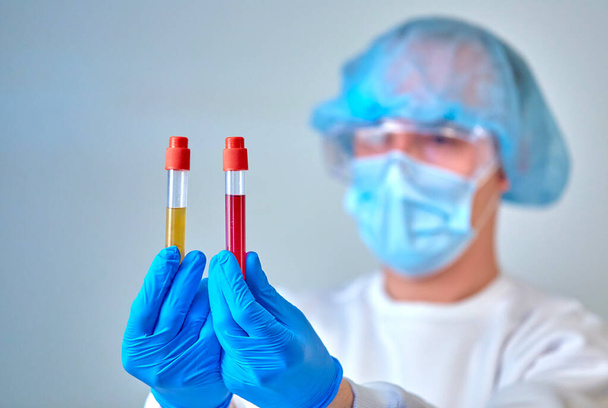 Doctor in mask holding the blood test tubes, coronavirus COVID19, HIV, ebola or other dangerous infection. Medical background, instruments, template, wallpaper. Coronavirus disease concept. Doctor portrait - Foto, Imagen