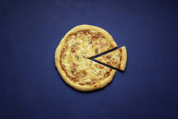 Pizza quattro formaggi hecha en casa. Pizza rebanada sobre un fondo azul, por encima de la vista. Pizza italiana hecha con 4 tipos de queso
. - Foto, Imagen