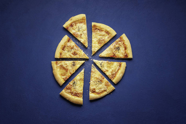 Pizza quattro formaggi otthon készült. Szeletelt pizza kék háttérrel, a kilátás felett. Olasz pizza 4 féle sajttal. - Fotó, kép