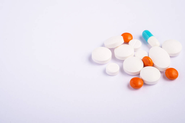 Pillen en tabletten op heldere witte achtergrond, medische zorg concept, antibiotica en genezing, hoek uitzicht kopieerruimte - Foto, afbeelding