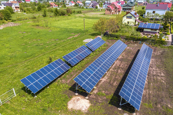 Pannelli solari blu foto voltaic montati su telaio in metallo in piedi a terra con erba verde in campo
. - Foto, immagini