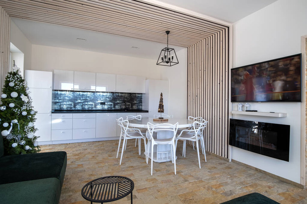Intérieur d'une cuisine spacieuse moderne avec murs blancs, éléments décoratifs en bois, mobilier contemporain et grand canapé doux
. - Photo, image