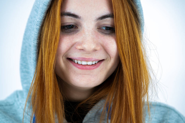 Close up portrait of happy smiling young redhead woman wearing warm hoodie pullover. - Foto, afbeelding