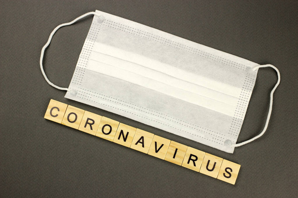 Medical mask, respiratory bandage face for protection against diseases and the inscription Coronavirus in wooden letters - Photo, Image