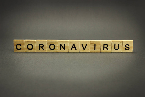 Inscription coronavirus in wooden letters on a grey background. Dangerous 2019-nCov flu infection - Photo, Image