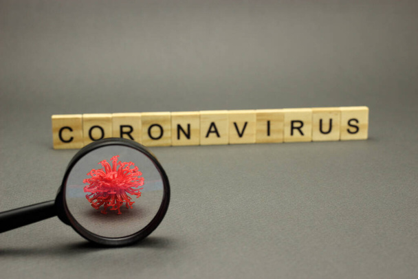 灰色の背景とクラウンモデル上の木製の文字で碑文コロナウイルス。危険な2019-nConvインフルエンザ感染症 - 写真・画像